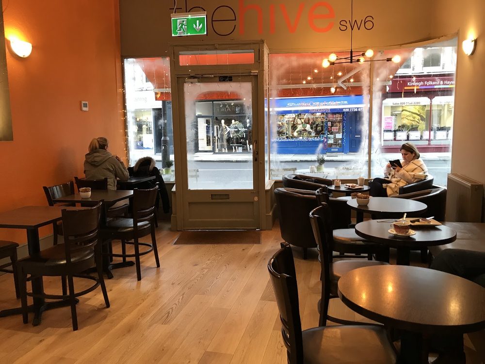 Inside the cafe looking out through the glass shopfront onto Fulham Road, wooden tables in the foreground