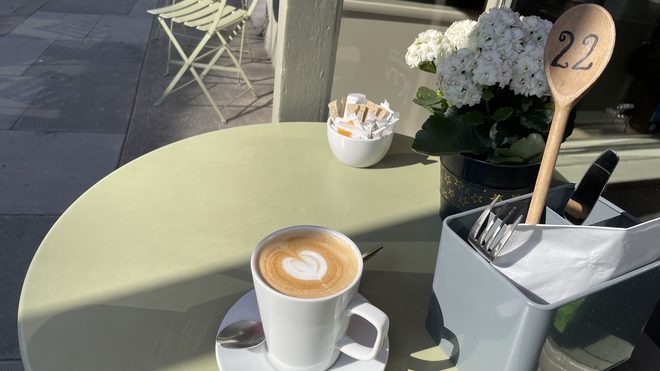 A coffee on a pale table with a table number, white hydrangeas and a cutlery caddy