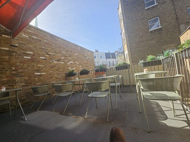The back terrace with metal tables against a brick wall